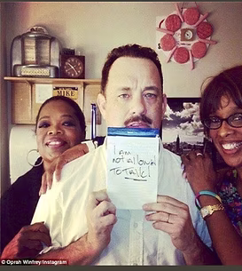 Photo shared by Oprah Winfrey on Instagram of Tom Hanks holding a sign reading 'I am not allowed to talk'